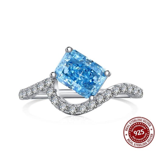 Ring with blue gemstone and diamond accents on a white background, featuring a '925 Real Sterling Silver' stamp.