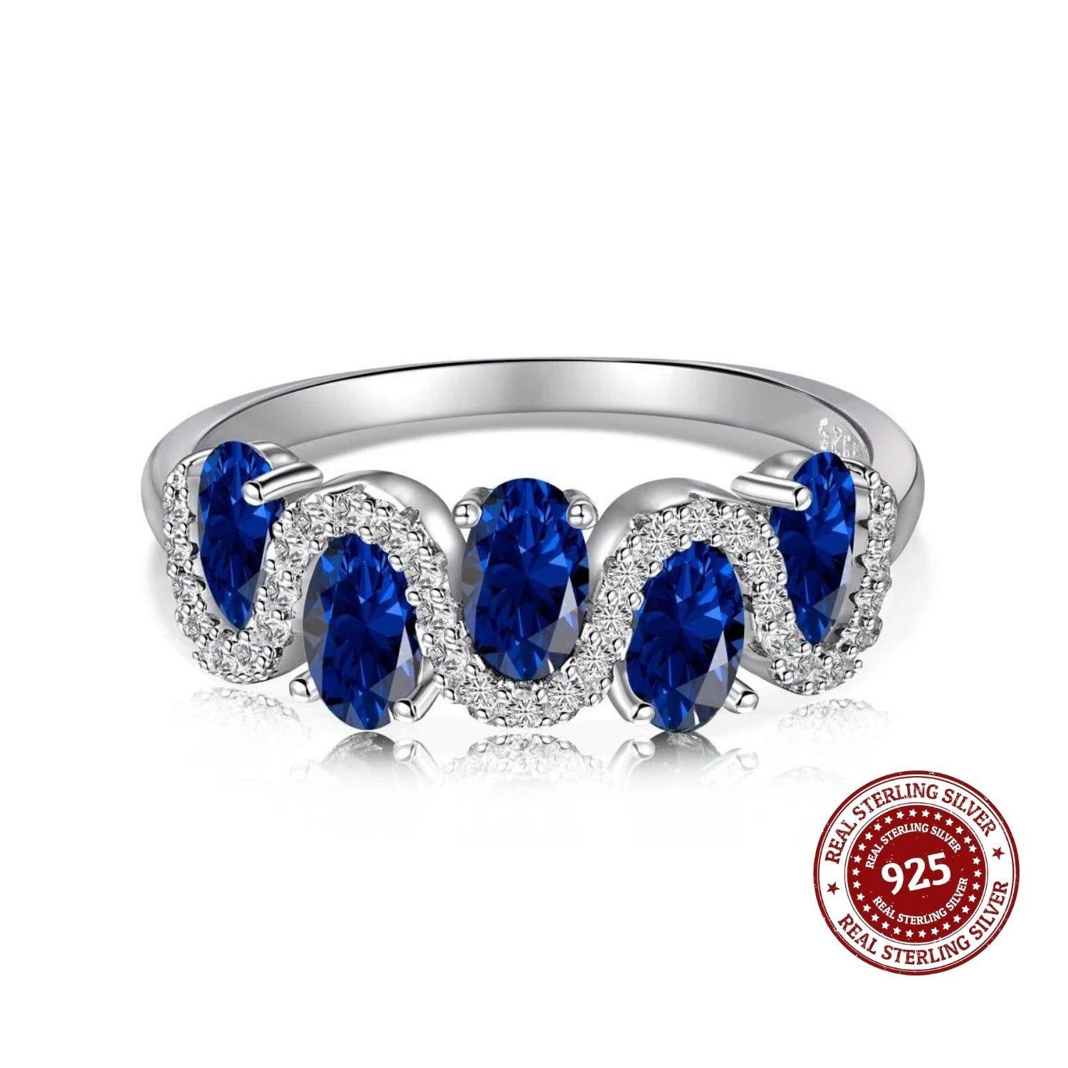 Silver ring with blue gemstones on a white background, featuring a 'Real Sterling Silver 925' stamp.