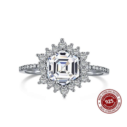 Silver ring with a large diamond and smaller diamonds on the band, on a white background.